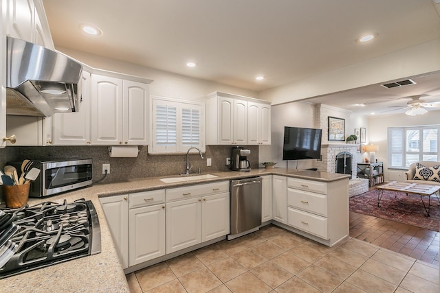 kitchen with visible vents, appliances with stainless steel finishes, open floor plan, a sink, and ventilation hood