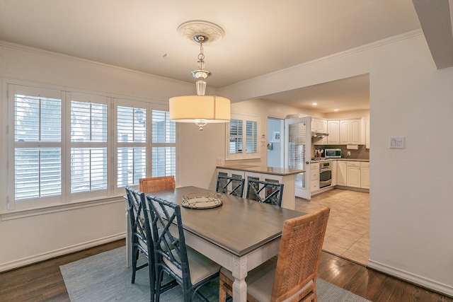 dining space featuring baseboards, crown molding, and wood finished floors