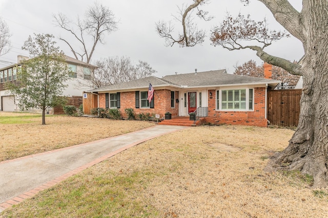 view of front of house with a front lawn, a shingled roof, fence, and brick siding