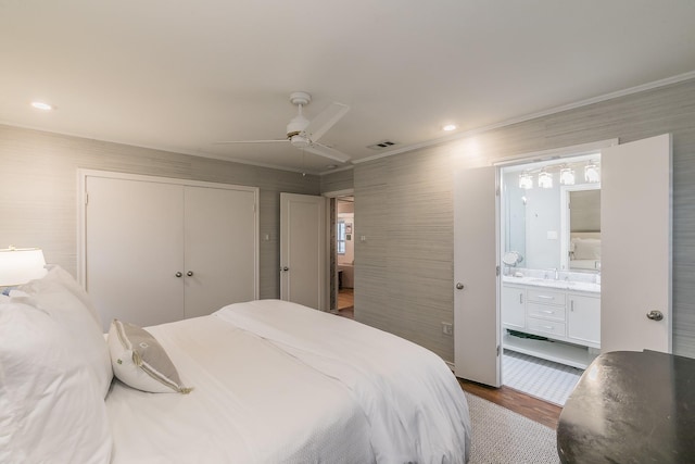 bedroom with dark wood-style flooring, a sink, visible vents, ornamental molding, and a closet