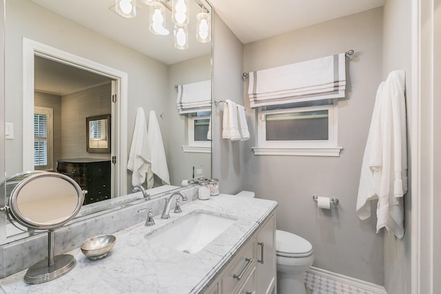 bathroom with toilet, an inviting chandelier, baseboards, and vanity