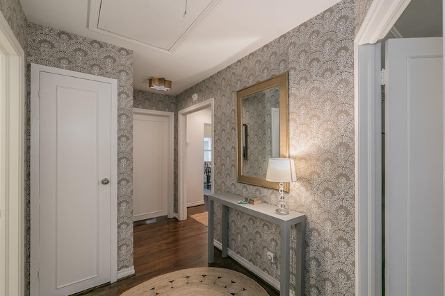 hallway with wallpapered walls, attic access, baseboards, and dark wood finished floors