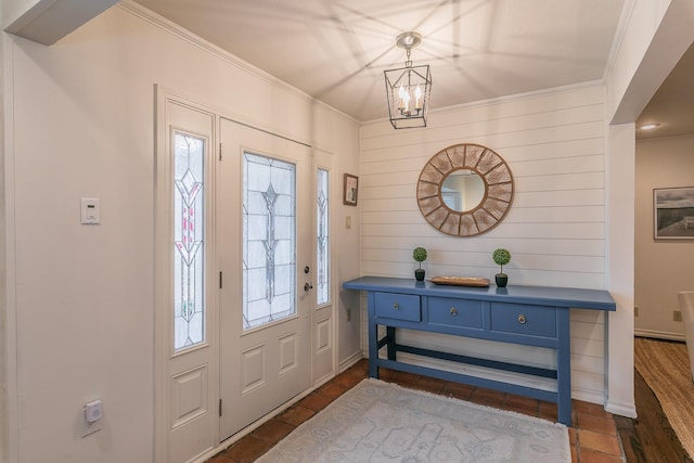 entryway featuring a notable chandelier, dark wood finished floors, and crown molding