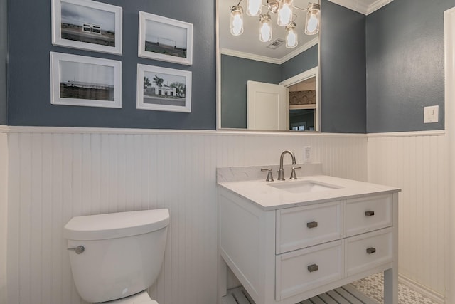 bathroom with a wainscoted wall, crown molding, visible vents, toilet, and vanity