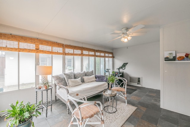 living room featuring ceiling fan, stone finish floor, and a healthy amount of sunlight