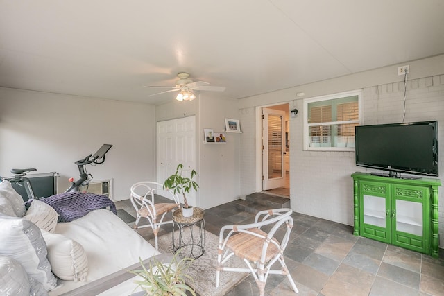 living area with a ceiling fan and stone finish floor