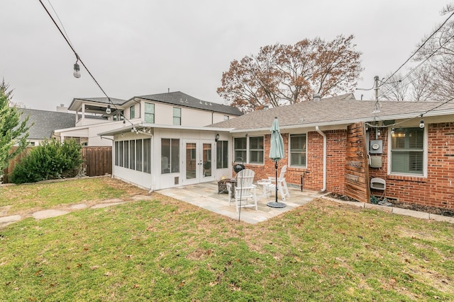 rear view of house with french doors, brick siding, a yard, a patio, and fence