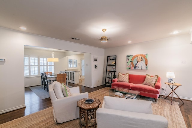 living room with recessed lighting, visible vents, baseboards, and wood finished floors