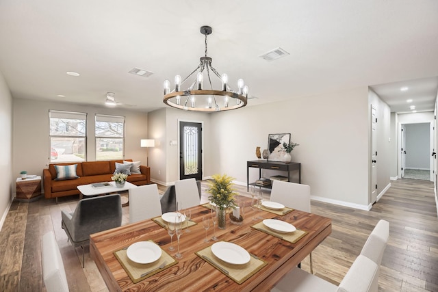 dining room featuring hardwood / wood-style flooring, baseboards, visible vents, and a notable chandelier