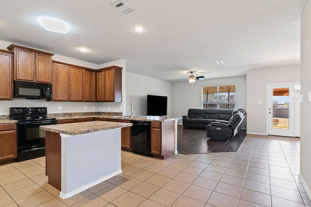 kitchen featuring light tile patterned floors, visible vents, open floor plan, a sink, and black appliances