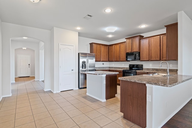 kitchen featuring arched walkways, a sink, visible vents, black appliances, and brown cabinetry