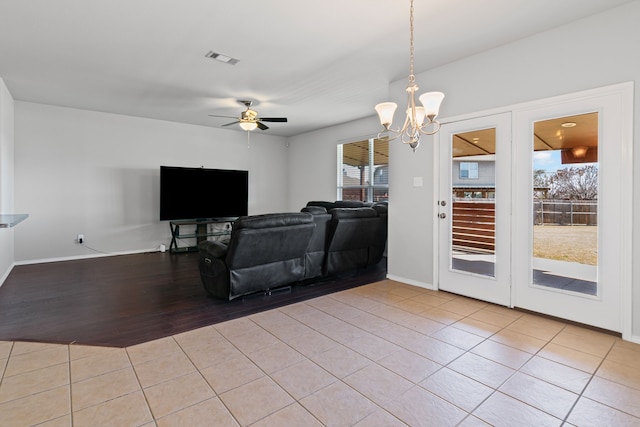 living room with ceiling fan with notable chandelier, visible vents, baseboards, and light tile patterned flooring