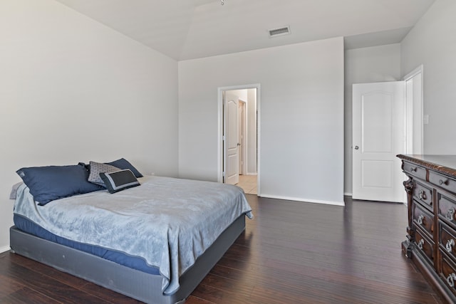 bedroom with lofted ceiling, wood finished floors, visible vents, and baseboards