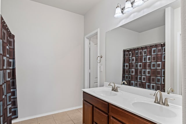 bathroom featuring double vanity, a sink, baseboards, and tile patterned floors