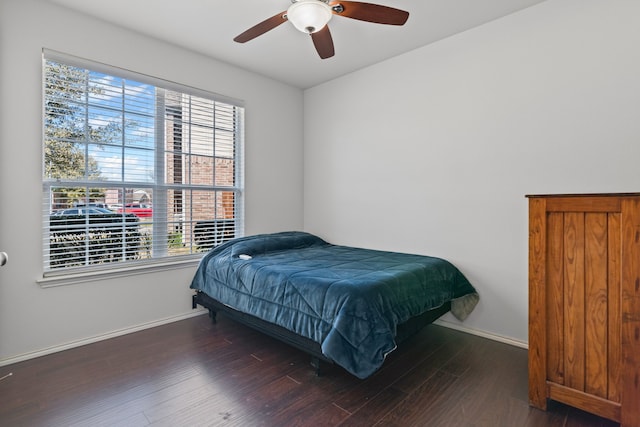 bedroom featuring a ceiling fan, multiple windows, baseboards, and wood finished floors