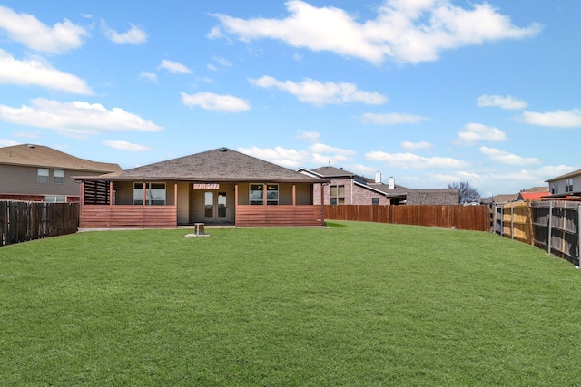 rear view of property with a fenced backyard and a lawn