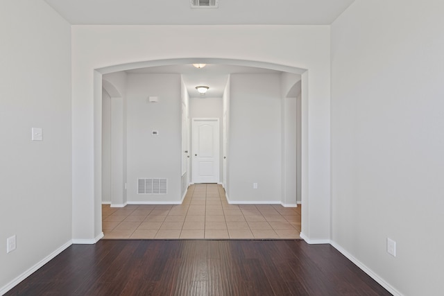 interior space with arched walkways, visible vents, baseboards, and wood finished floors