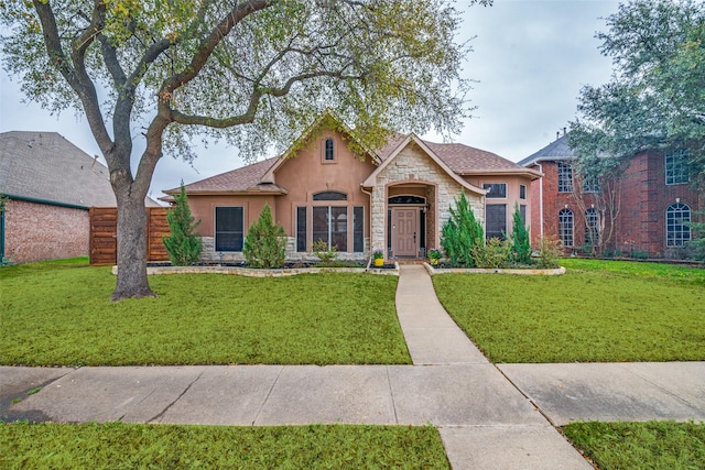 view of front of home featuring stone siding, a front yard, fence, and stucco siding