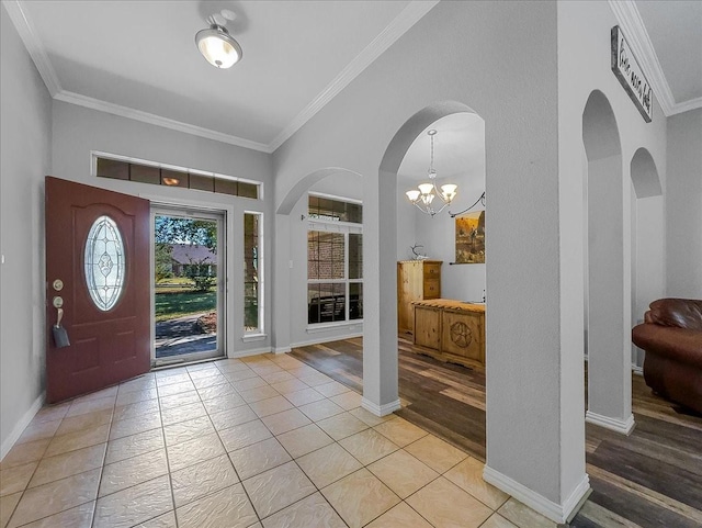 foyer entrance with light tile patterned floors, a chandelier, arched walkways, baseboards, and crown molding