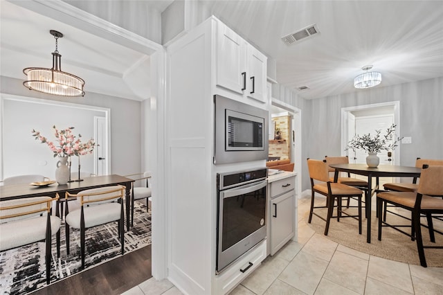 kitchen featuring white cabinets, appliances with stainless steel finishes, visible vents, and an inviting chandelier