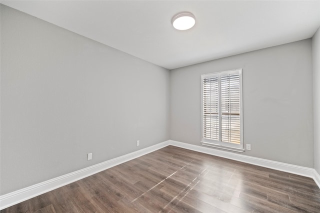 unfurnished room with dark wood-type flooring and baseboards