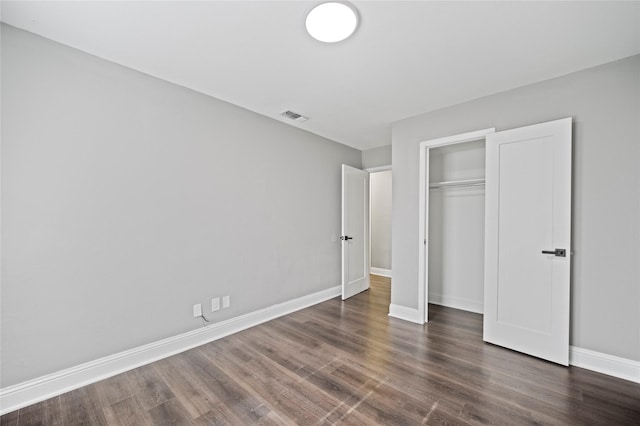 unfurnished bedroom featuring a closet, wood finished floors, visible vents, and baseboards