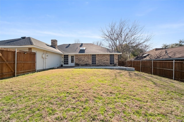 rear view of property featuring a yard and a fenced backyard