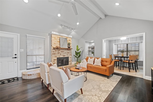 living area with a brick fireplace, plenty of natural light, beamed ceiling, and wood finished floors