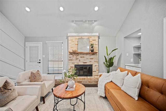 living area featuring a fireplace, vaulted ceiling, track lighting, and recessed lighting