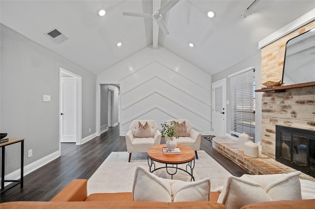 living room with lofted ceiling with beams, wood finished floors, visible vents, baseboards, and a brick fireplace