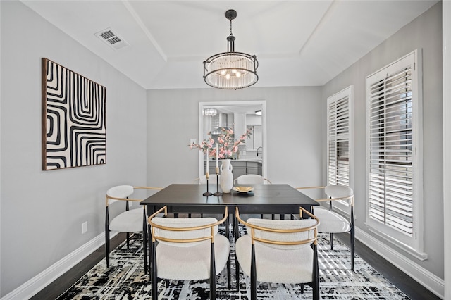 dining area featuring an inviting chandelier, visible vents, baseboards, and wood finished floors