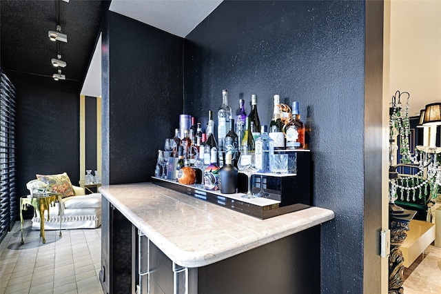 bar with a bar, tile patterned flooring, and a textured wall