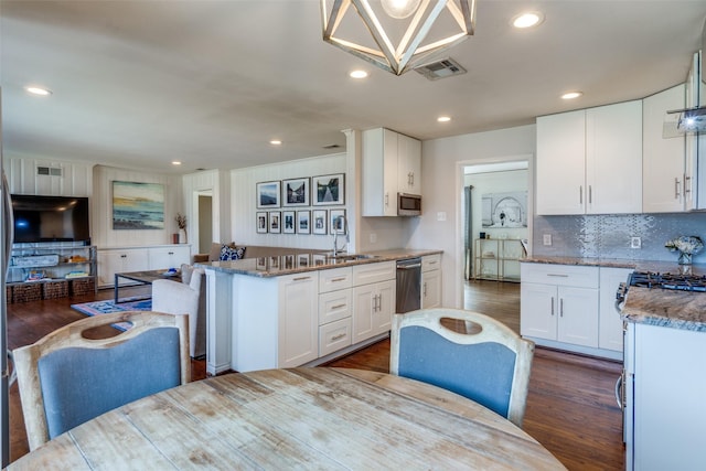 kitchen with dark wood-style flooring, a sink, visible vents, and white cabinetry