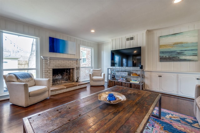 living area featuring dark wood-style floors, a fireplace, crown molding, visible vents, and a decorative wall