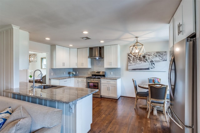 kitchen featuring stone countertops, visible vents, wall chimney exhaust hood, stainless steel appliances, and a sink