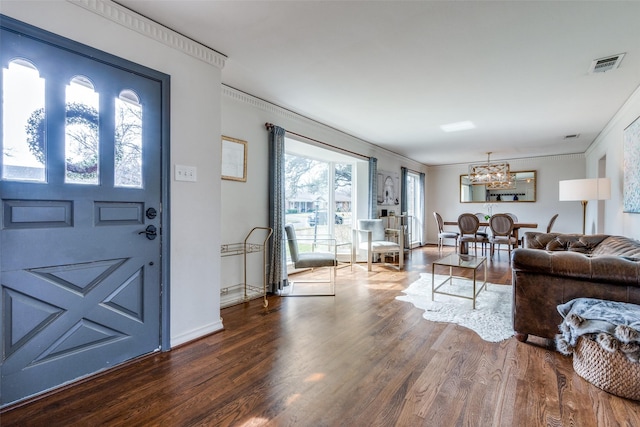 foyer entrance featuring crown molding, visible vents, an inviting chandelier, wood finished floors, and baseboards