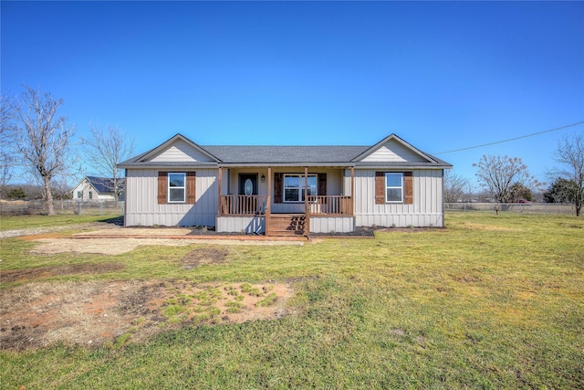 view of front of house featuring covered porch, board and batten siding, a front yard, and fence