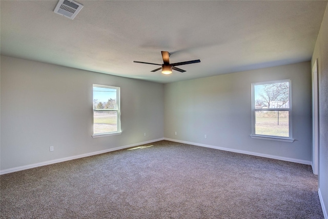 unfurnished room featuring visible vents, dark carpet, baseboards, and ceiling fan