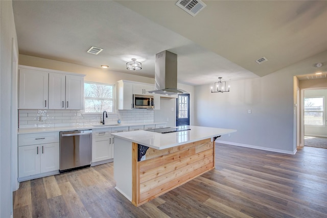 kitchen with a sink, appliances with stainless steel finishes, island exhaust hood, and visible vents