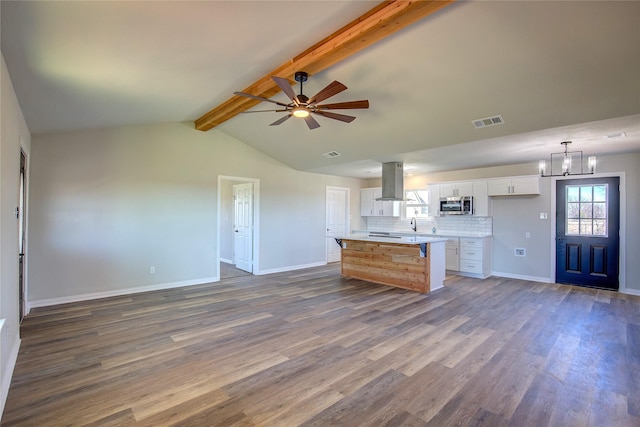 kitchen with a healthy amount of sunlight, stainless steel microwave, island exhaust hood, and white cabinetry