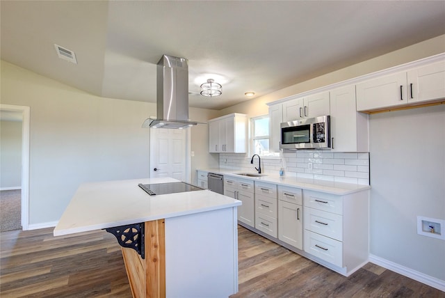 kitchen featuring visible vents, appliances with stainless steel finishes, a sink, a kitchen island, and island range hood