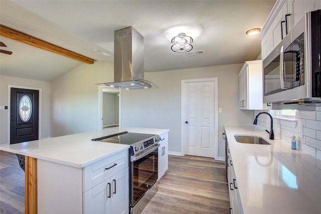 kitchen featuring island range hood, stainless steel appliances, a sink, visible vents, and light wood-style floors