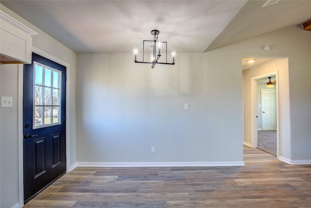 interior space with a notable chandelier, baseboards, vaulted ceiling, and wood finished floors