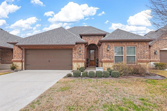 french provincial home featuring a shingled roof, concrete driveway, stone siding, an attached garage, and brick siding