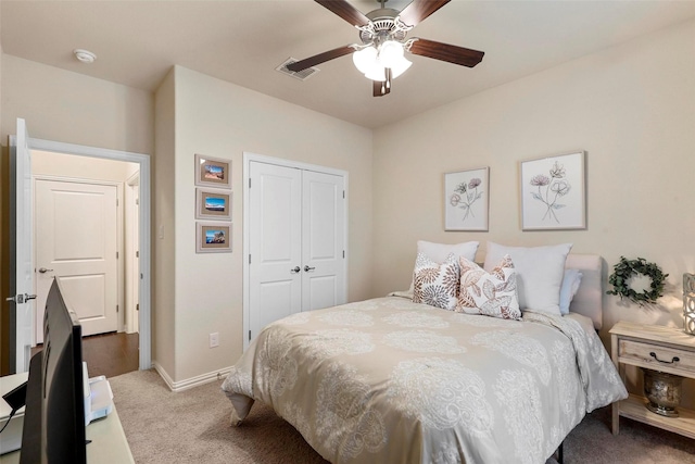 bedroom with baseboards, visible vents, light colored carpet, ceiling fan, and a closet