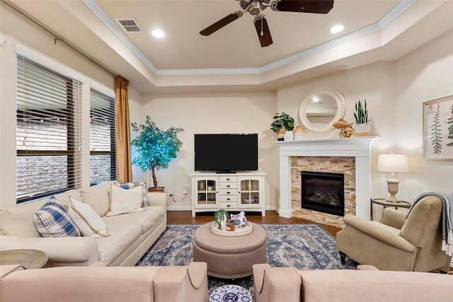 living area featuring baseboards, visible vents, wood finished floors, crown molding, and a fireplace