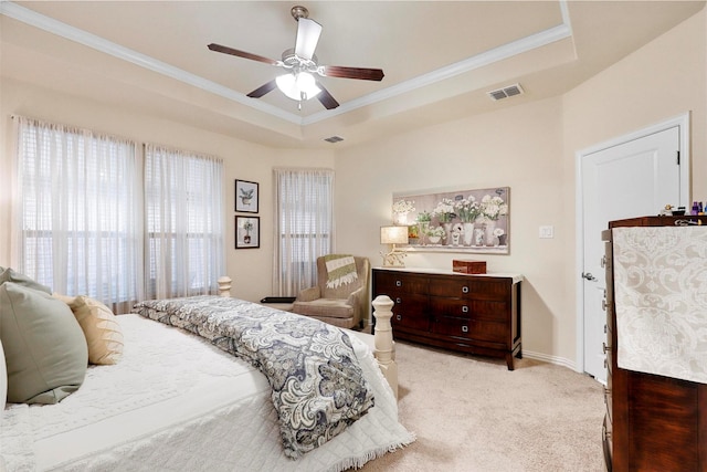 bedroom with carpet floors, a ceiling fan, visible vents, a tray ceiling, and crown molding