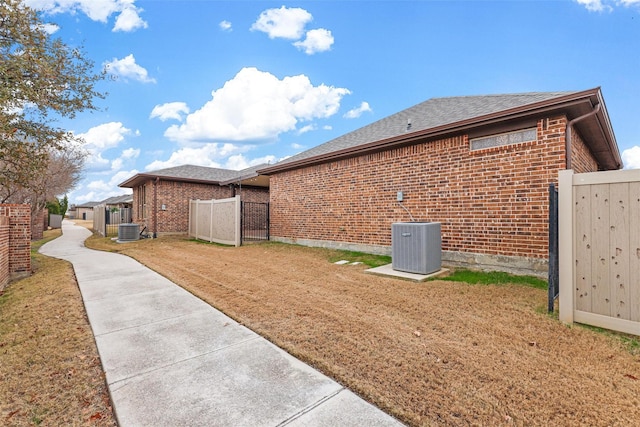 view of home's exterior with a lawn, cooling unit, and brick siding