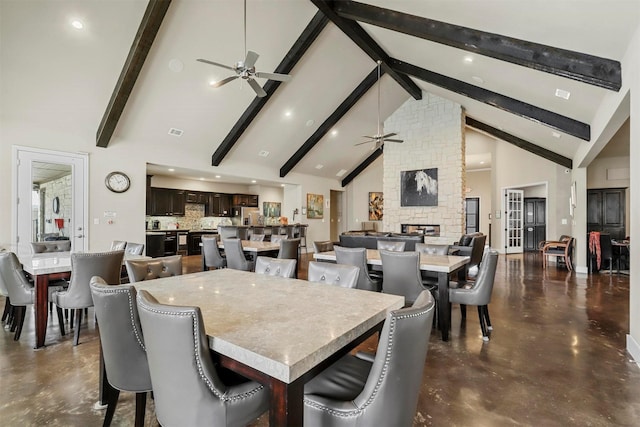 dining space featuring finished concrete flooring, high vaulted ceiling, a fireplace, and a ceiling fan