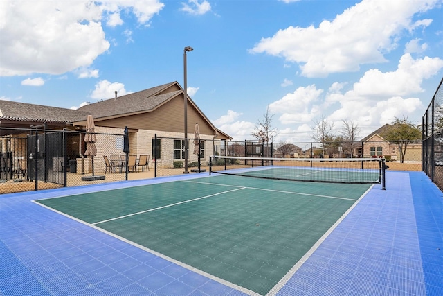 view of tennis court featuring community basketball court and fence